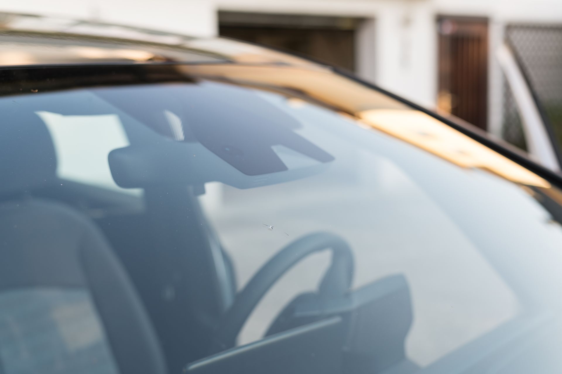 Close-up of a car windshield, revealing sensors and steering wheel inside.