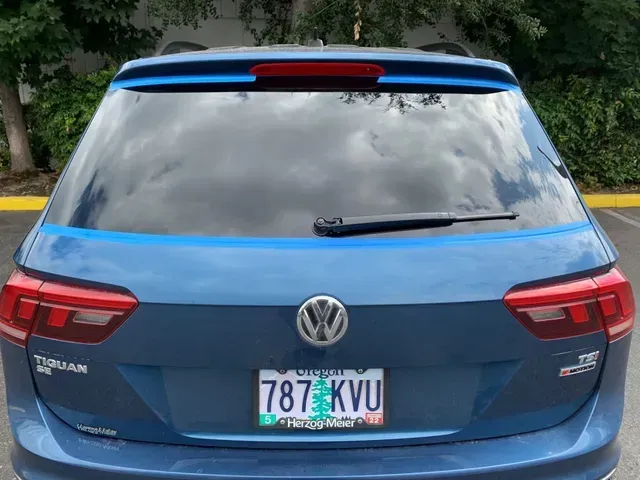 A blue Volkswagen Tiguan SUV seen from the rear, showing the VW logo, taillights, and Washington license plate 787 KVU.