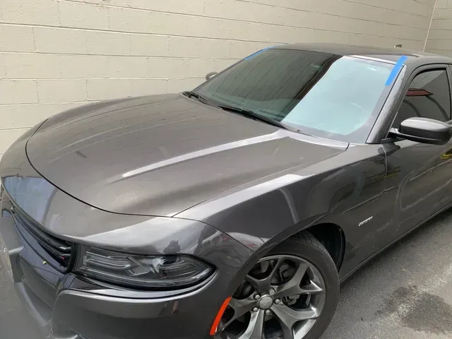 A gray Dodge Charger parked next to a light-colored concrete block wall.