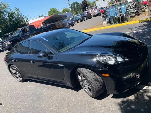 A black Porsche Panamera parked at an outdoor lot on a sunny day.
