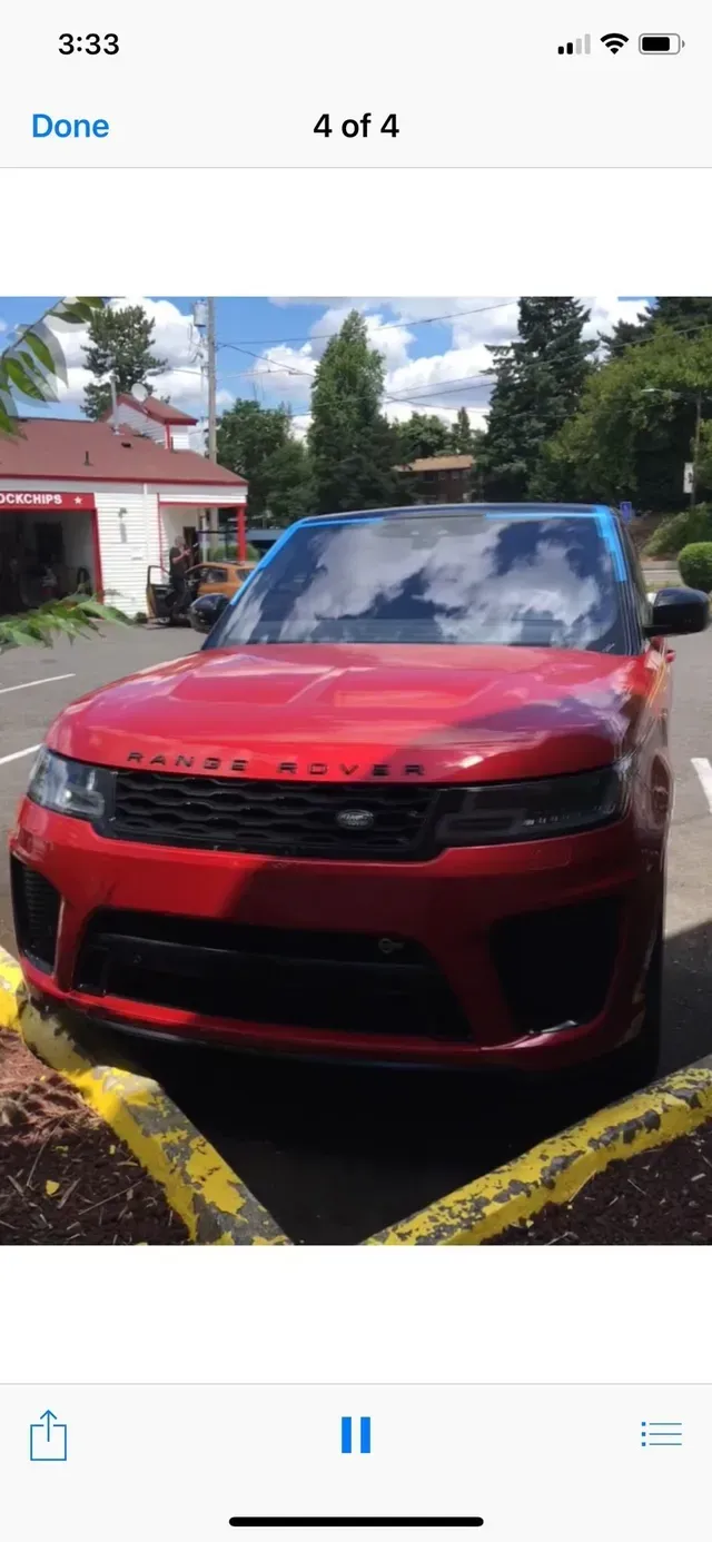 A red Range Rover parked in a lot under a blue sky.