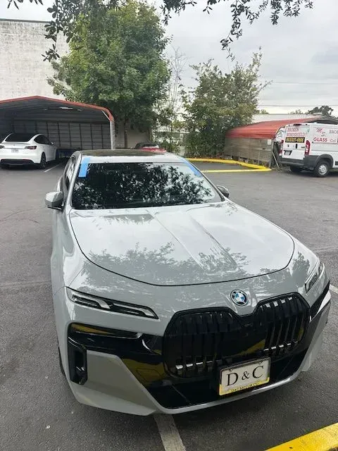 A grey BMW i7 sedan parked in an outdoor lot during the day, featuring its distinct front grille and headlights.