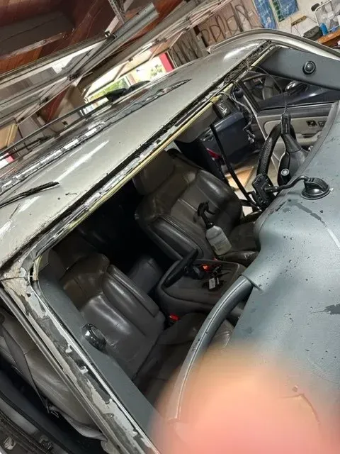 A close-up view of the interior and missing windshield area of a silver vehicle parked inside a garage.