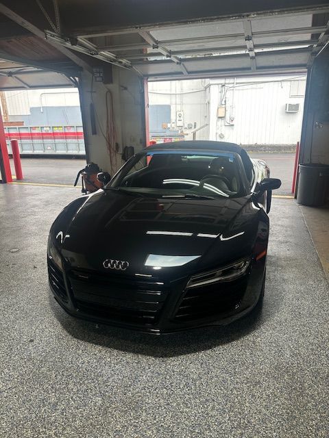 Black Audi sports car parked in a garage bay, front view