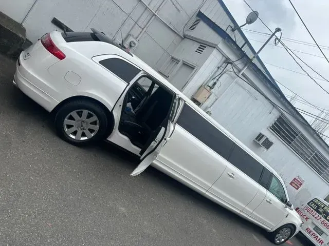 A white stretch limousine parked outside a commercial building with its passenger door open.
