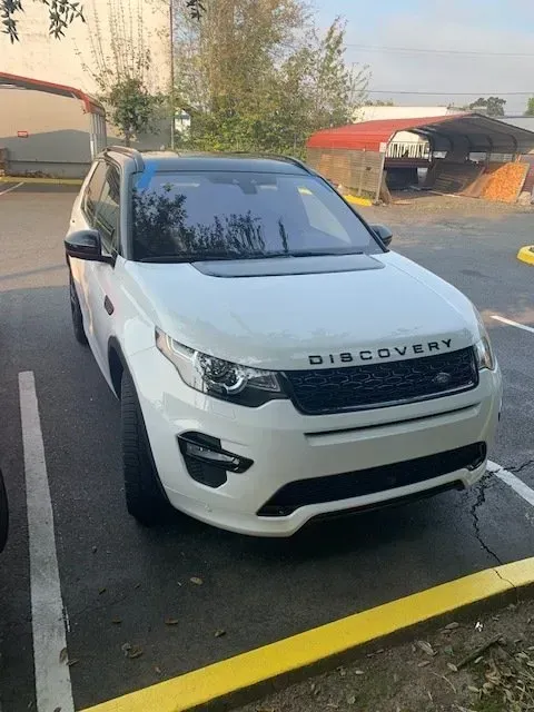 A white Land Rover Discovery parked in an outdoor lot on a sunny day.