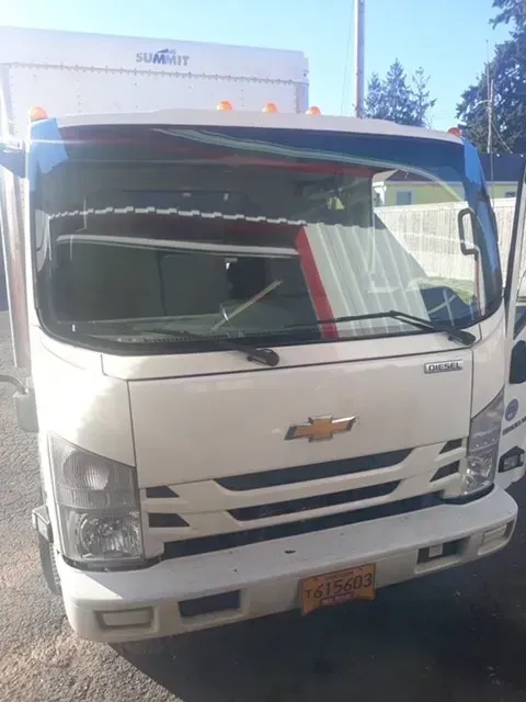 A white Chevrolet box truck parked outdoors, showing the front grille, headlights, and windshield.