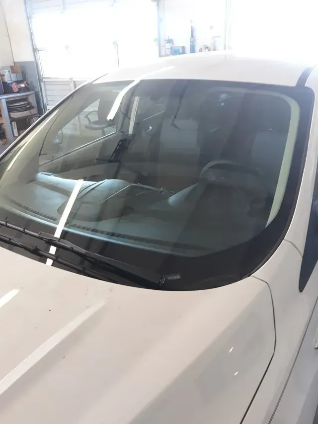 A close-up view of the white hood and windshield of a vehicle parked inside a garage.