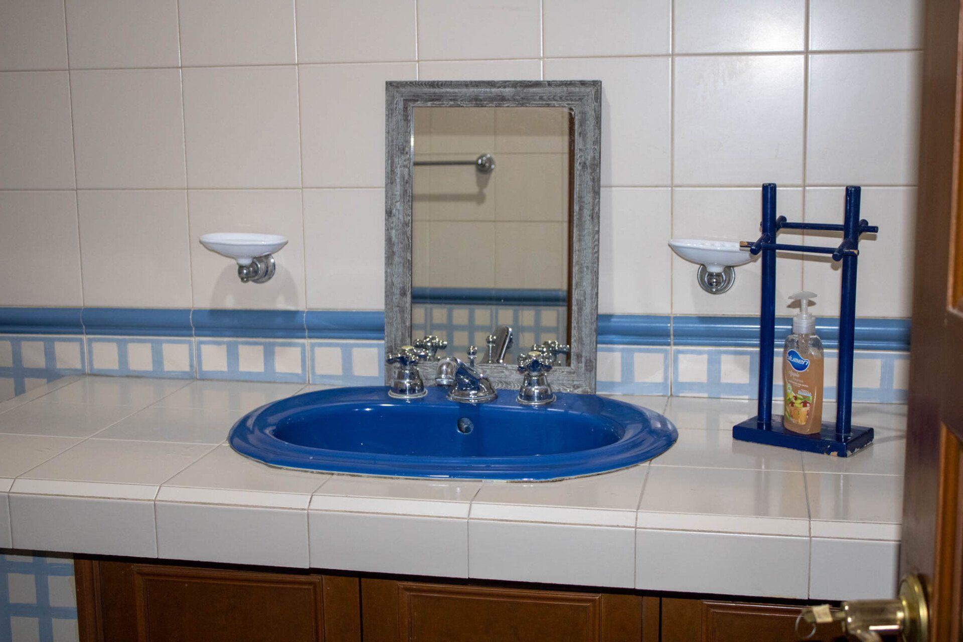 Un baño con un lavabo azul y un espejo.