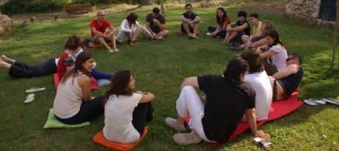 Un grupo de personas están sentadas en círculo sobre el césped.