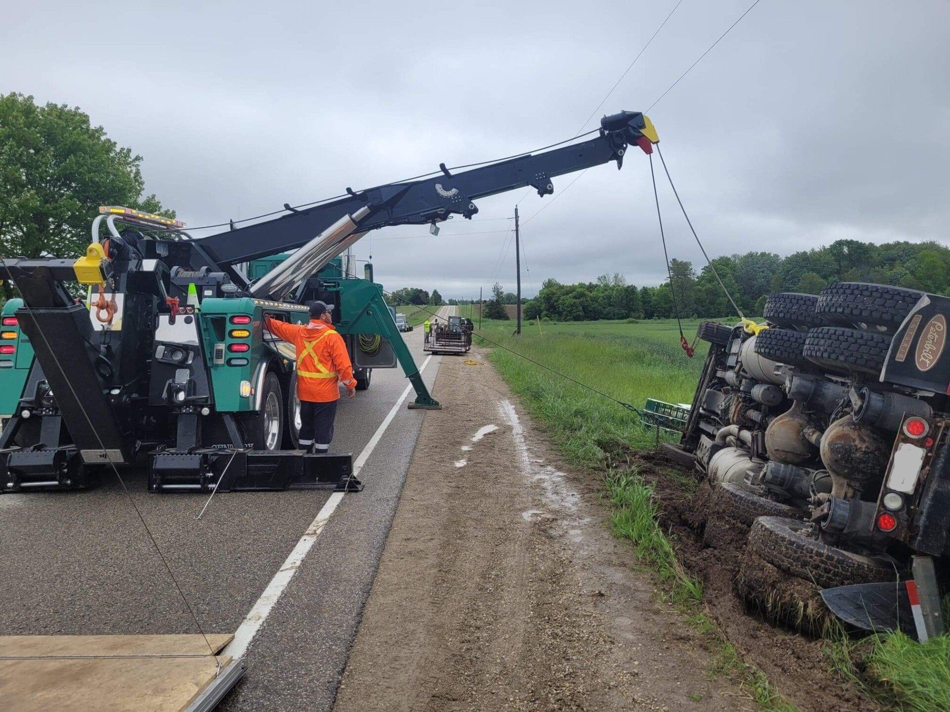 A tow truck is towing a truck that has fallen off the road.