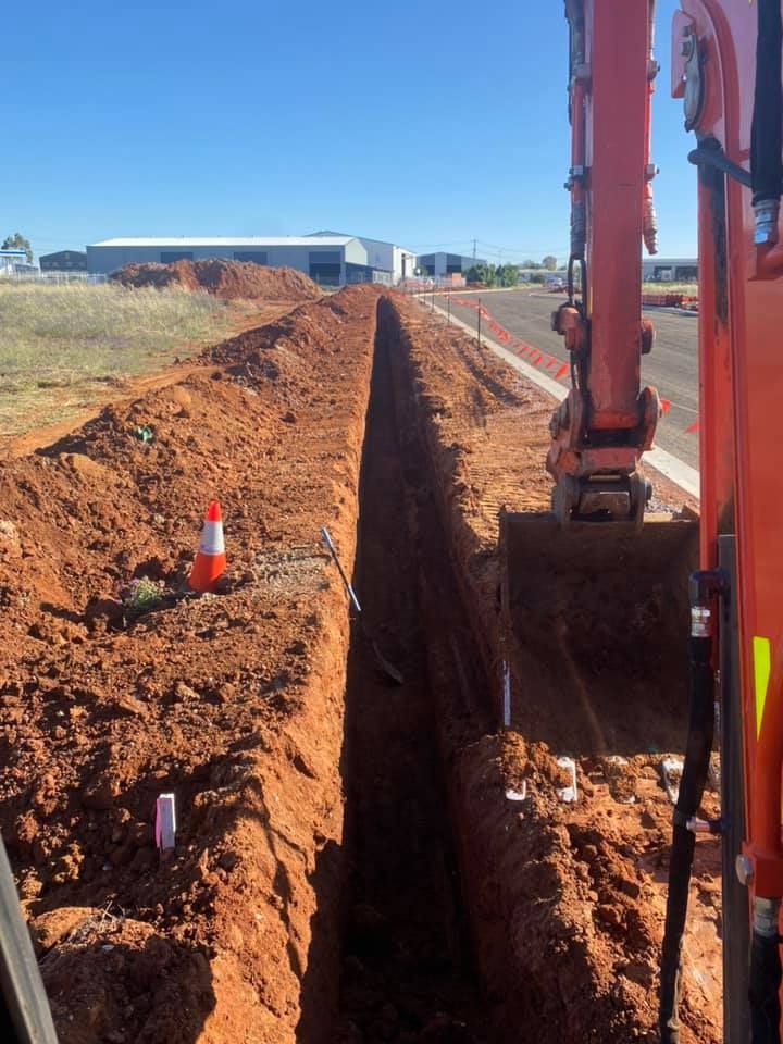 A Large Orange Excavator is Digging a Trench in the Dirt — RL Hire In Wellington, NSW
