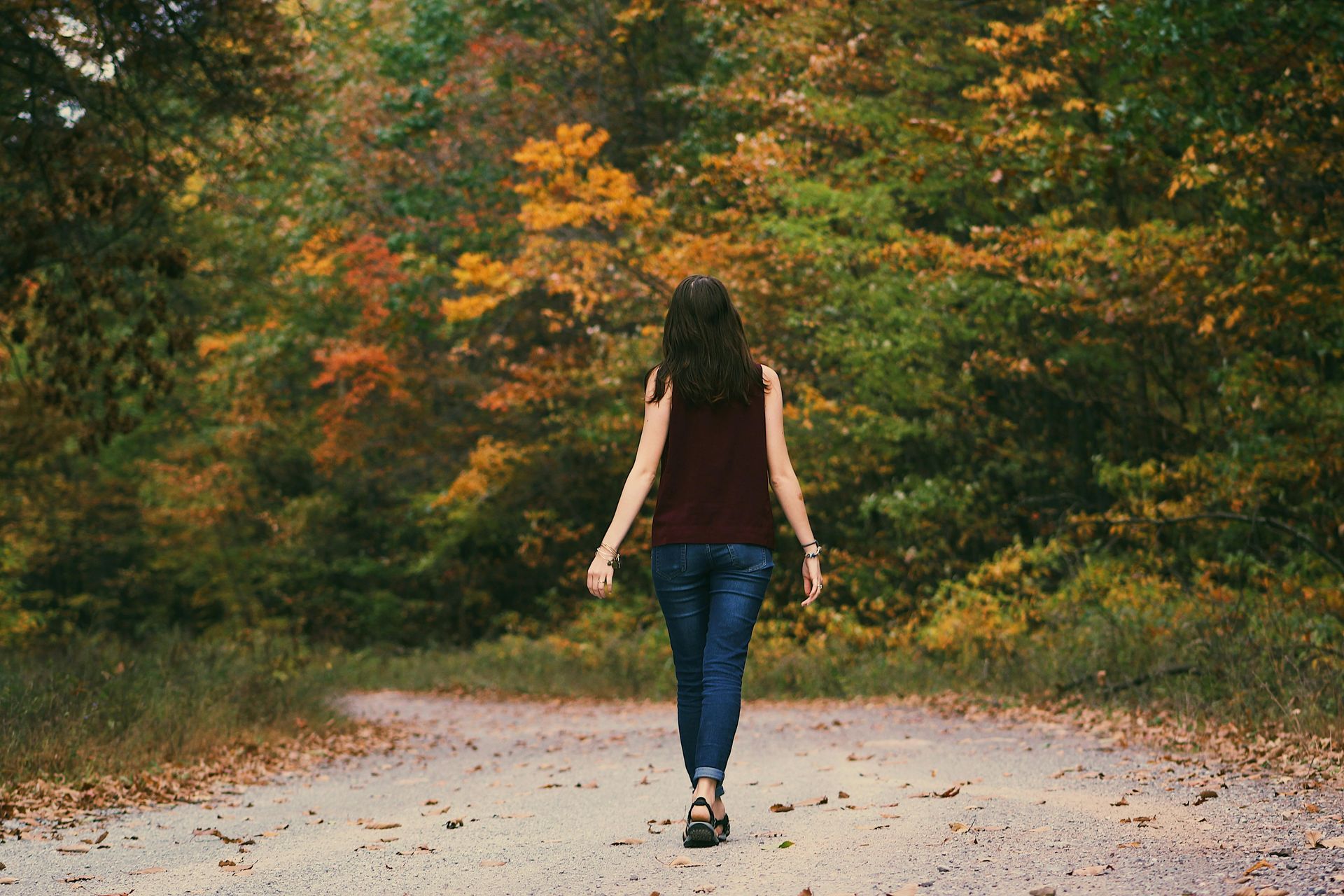Een vrouw loopt over een zandweg in het bos.