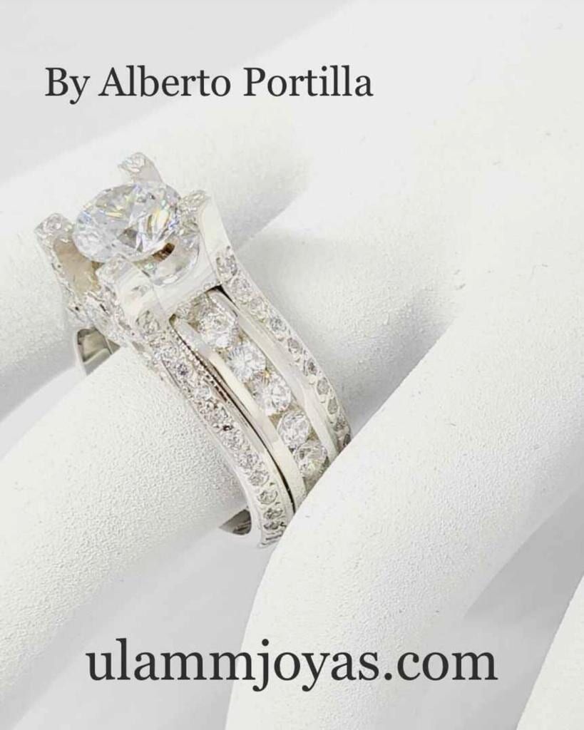 Un anillo de plata con un diamante en el centro se asienta sobre una superficie blanca