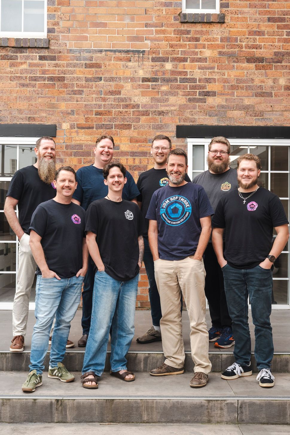 A group of men are posing for a picture in front of a brick building.