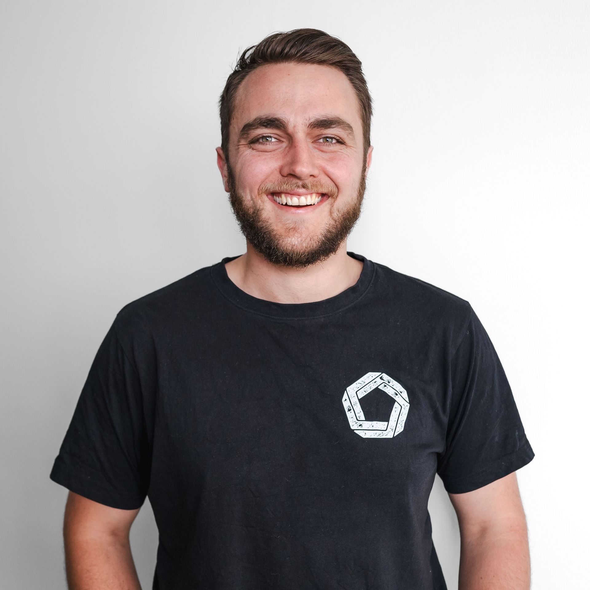 David Weekes with a beard is wearing a black t-shirt and smiling