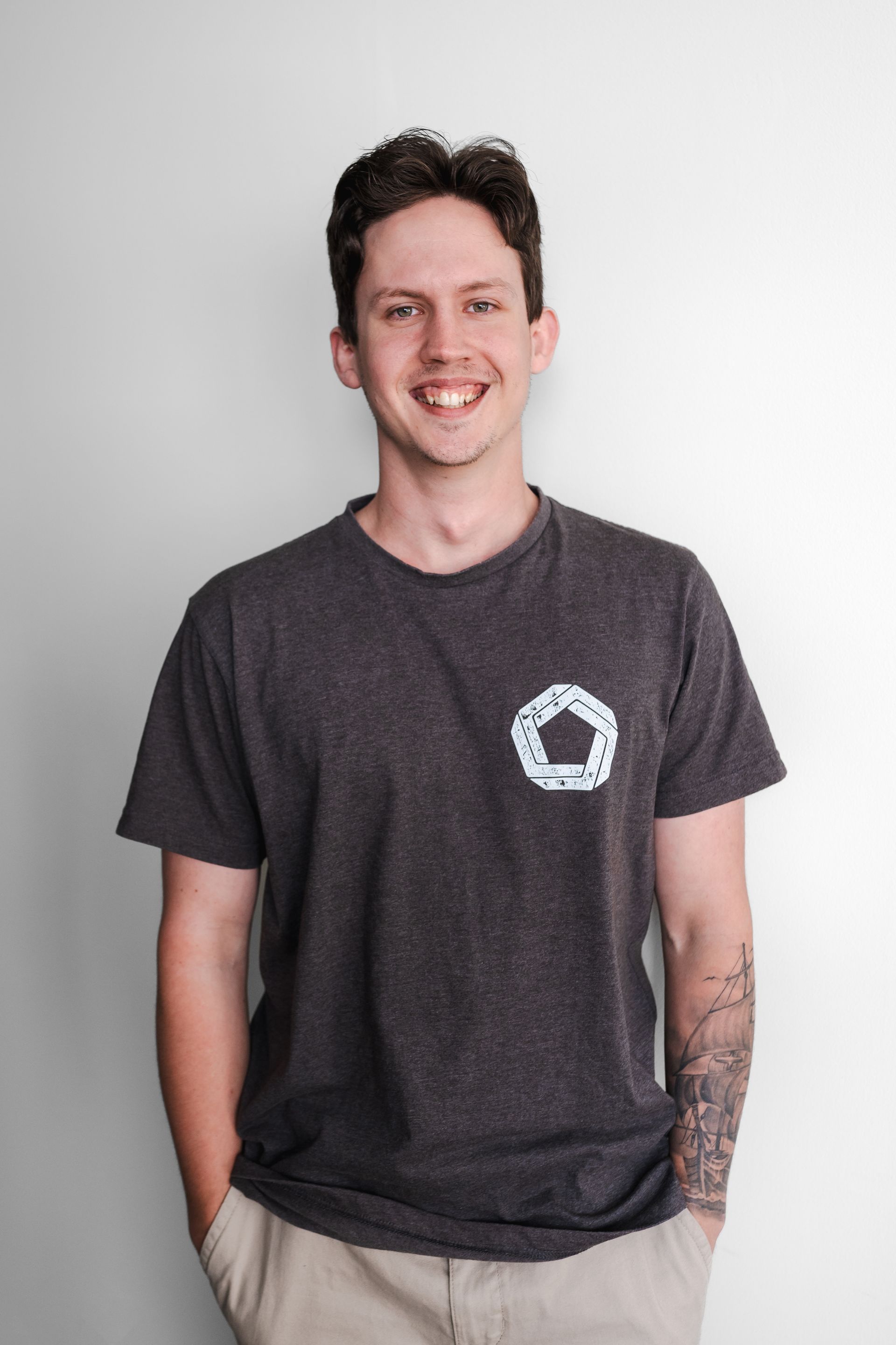 A man wearing a black t-shirt with a white circle on the front is smiling.