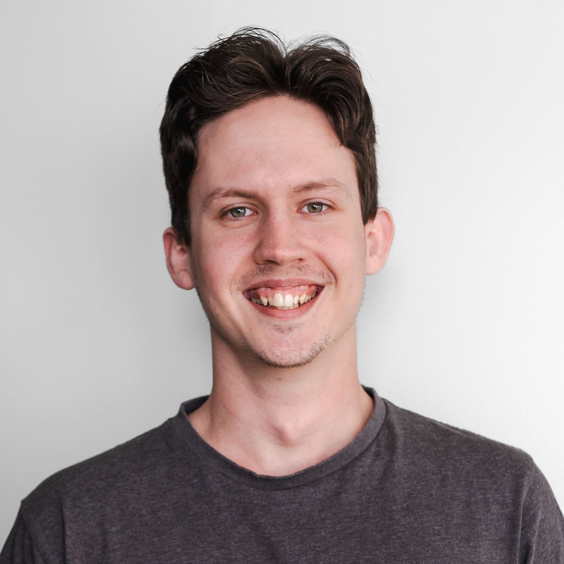 Ethan wearing a grey shirt is smiling for the camera.