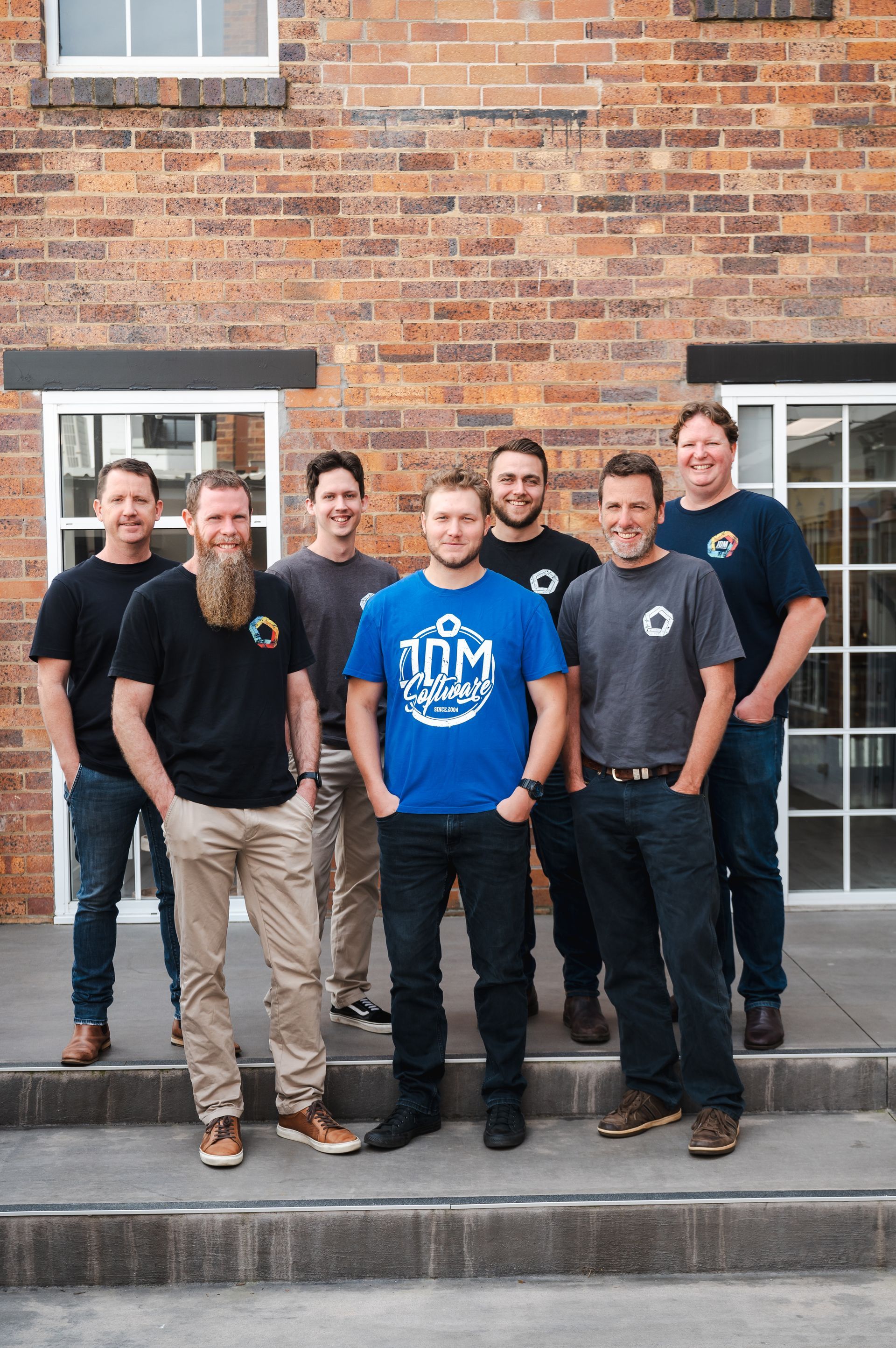 A group of men are posing for a picture in front of a brick building.