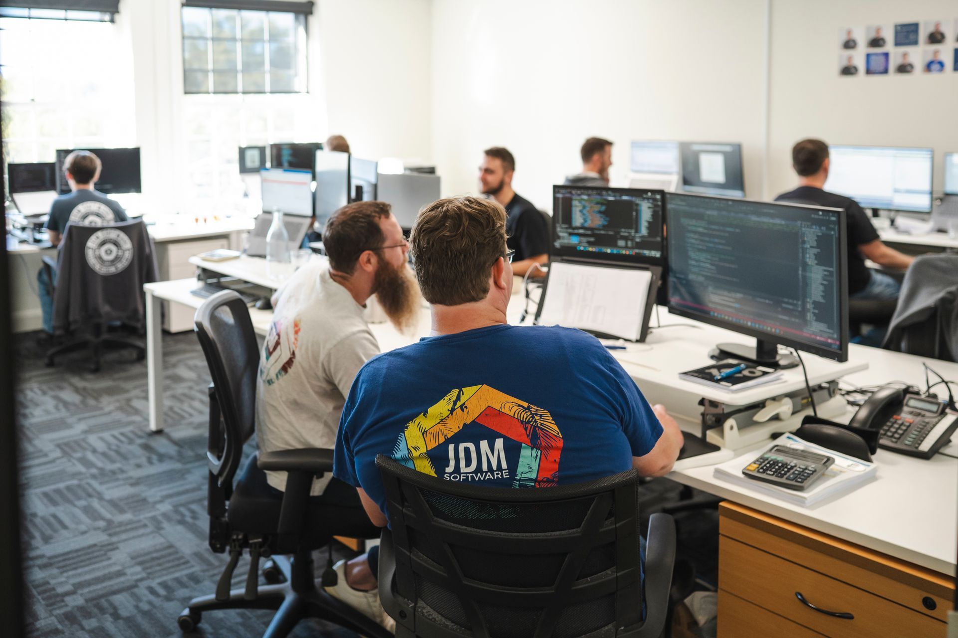 The JDM team are working at their computers, collaborating on custom software.