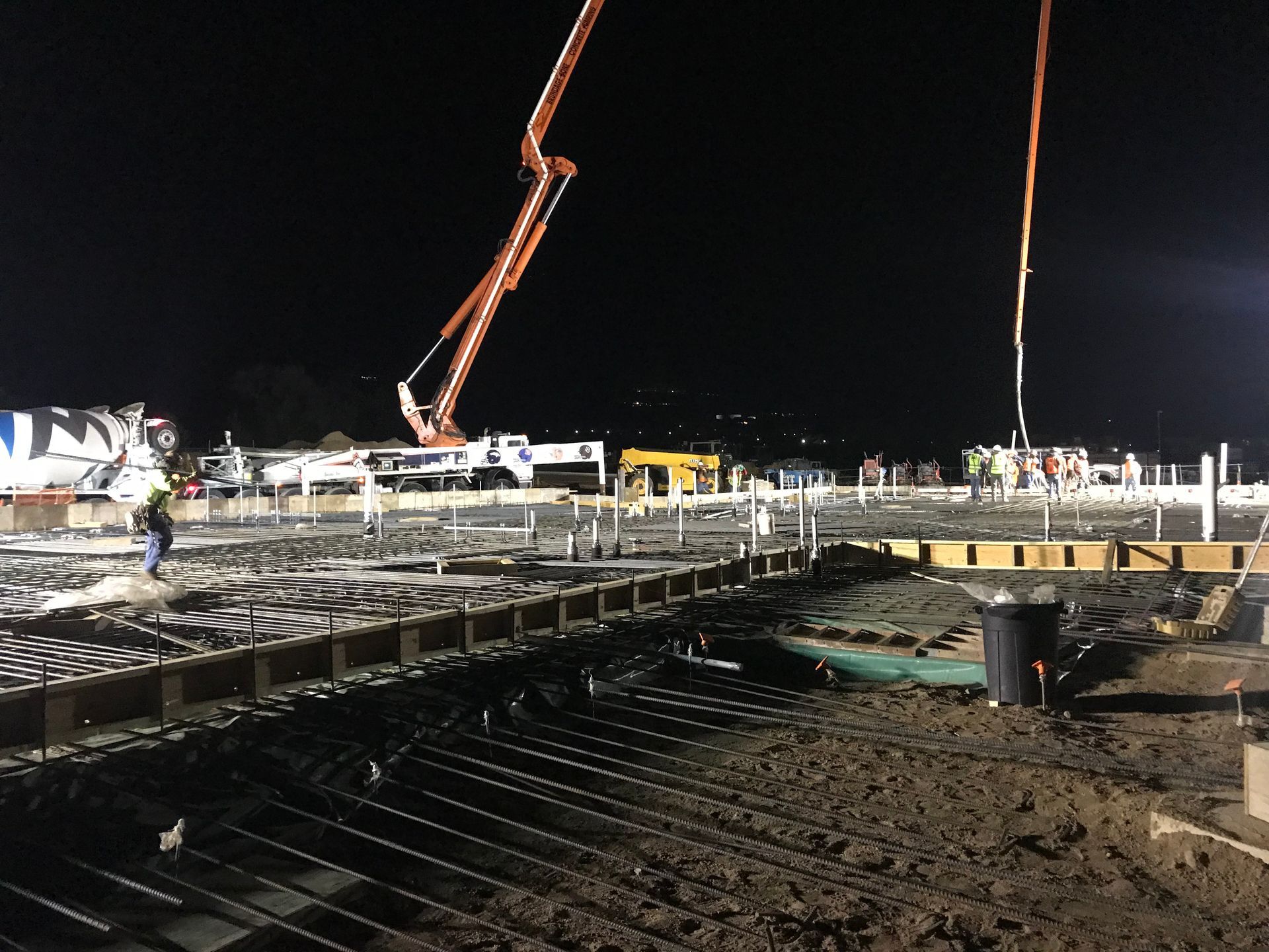 A construction site at night with a crane pumping concrete