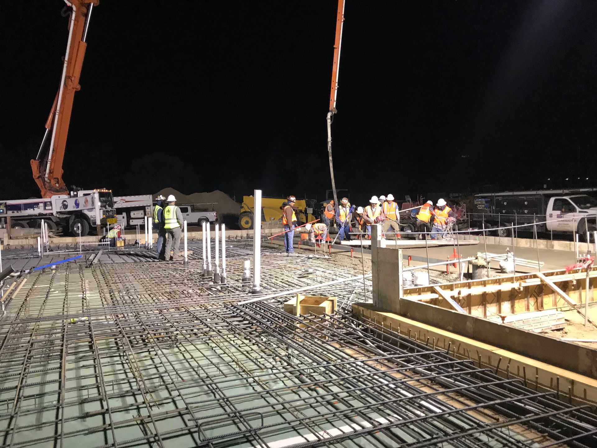 A group of construction workers are working on a construction site at night.