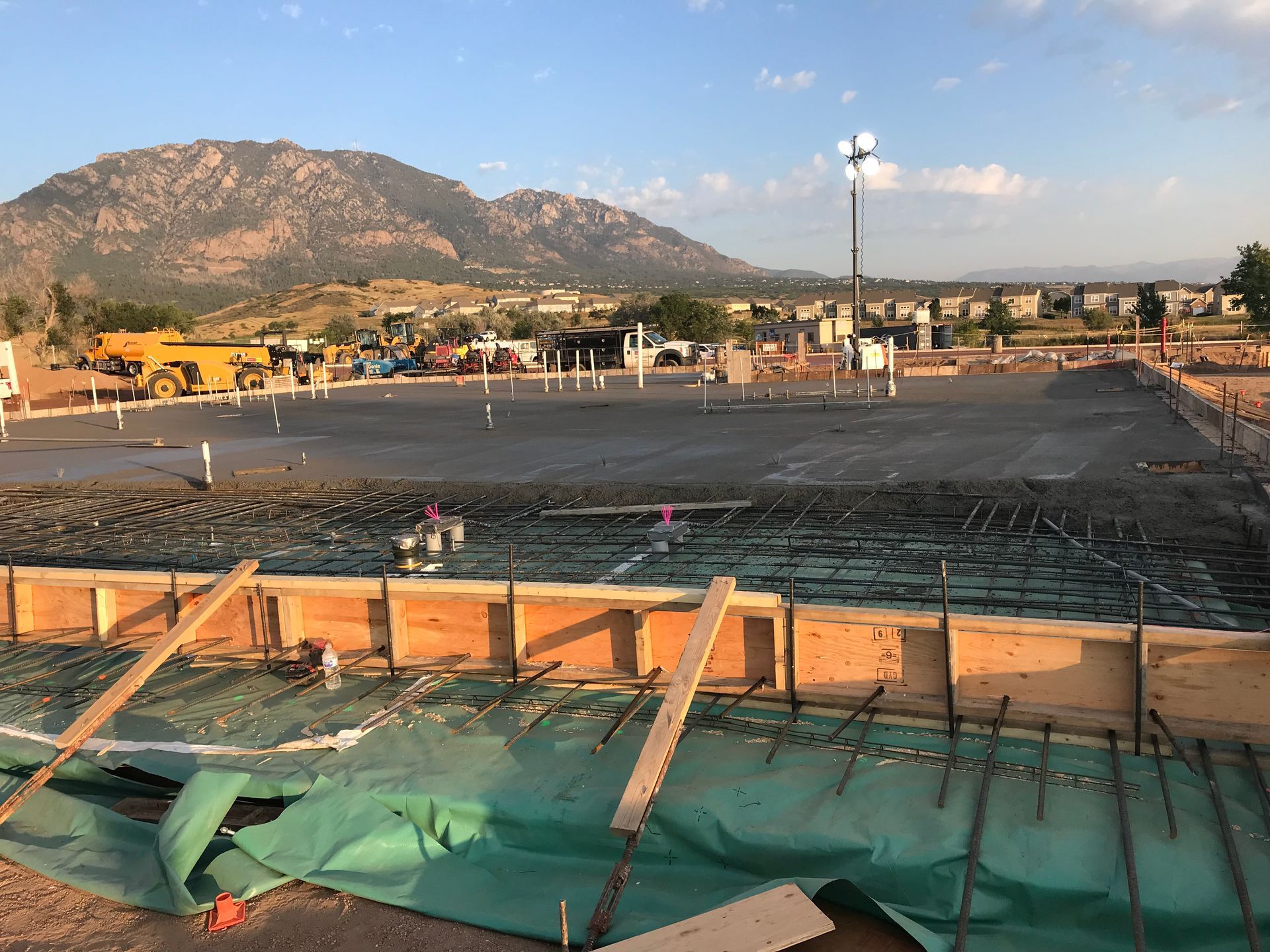 A construction site with mountains in the background and a green tarp on the ground.
