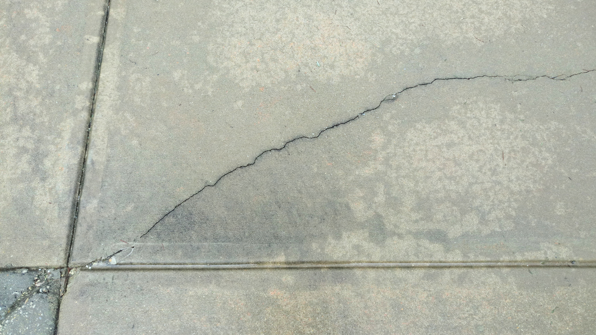 Crack forming across a concrete driveway surface in Aurora showing early signs of stress and damage.