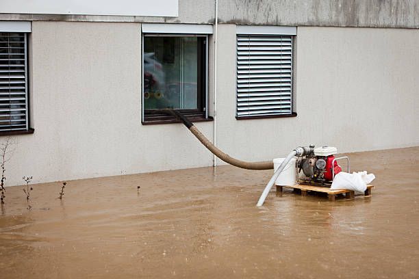 A water pump stands in a flooded street, highlighting post-flood cleaning and restoration efforts in the area.