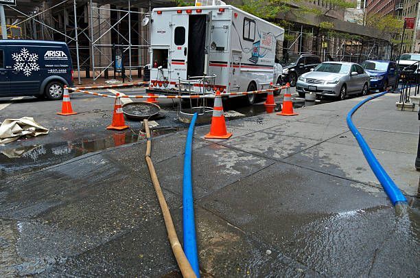 A blue garden hose lying on the pavement, used for water extraction, partially coiled and extending along the street.