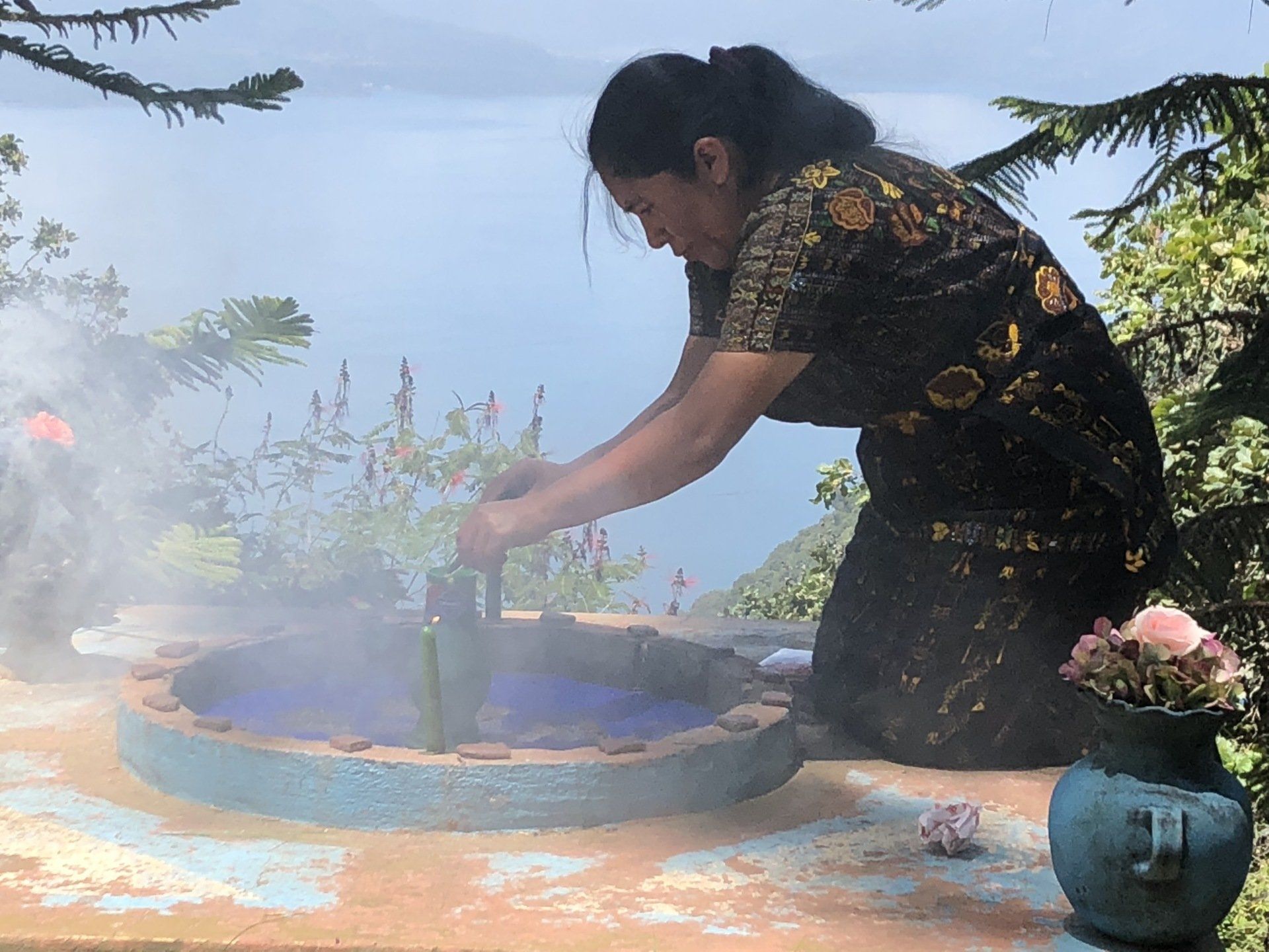 Eine Frau kniet vor einem Brunnen, aus dem Rauch aufsteigt