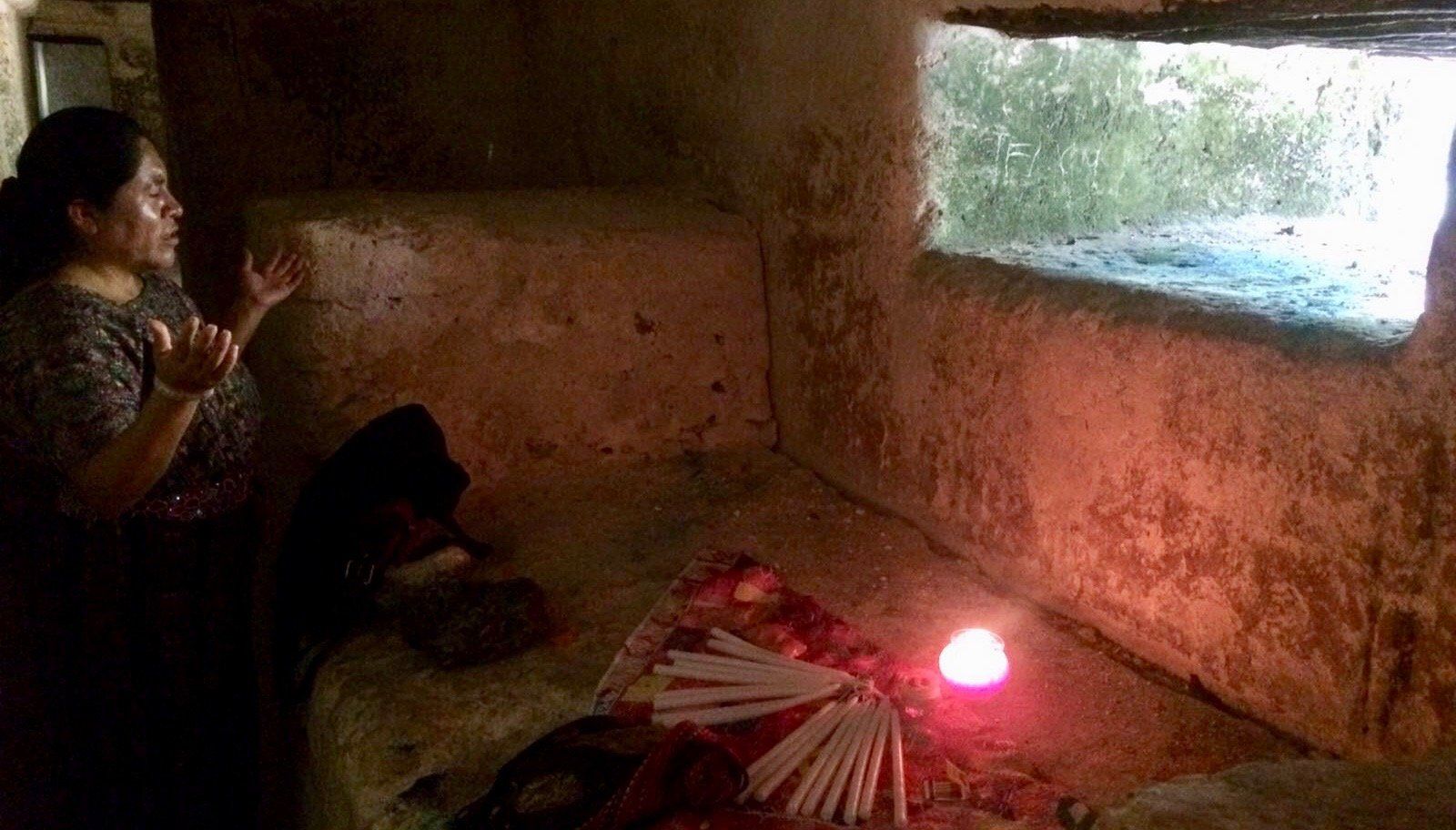 Eine Frau sitzt in einem Raum mit einer Kerze und einem Fenster.