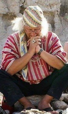 Ein Mann mit einem Schal um den Kopf sitzt auf einem Felsen.