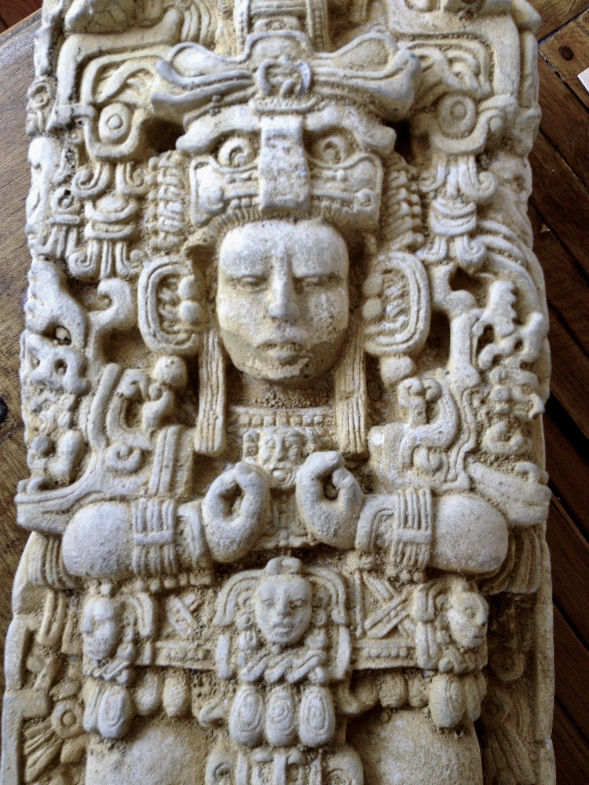 Auf einem Holztisch liegt eine Steinschnitzerei mit dem Gesicht einer Frau.