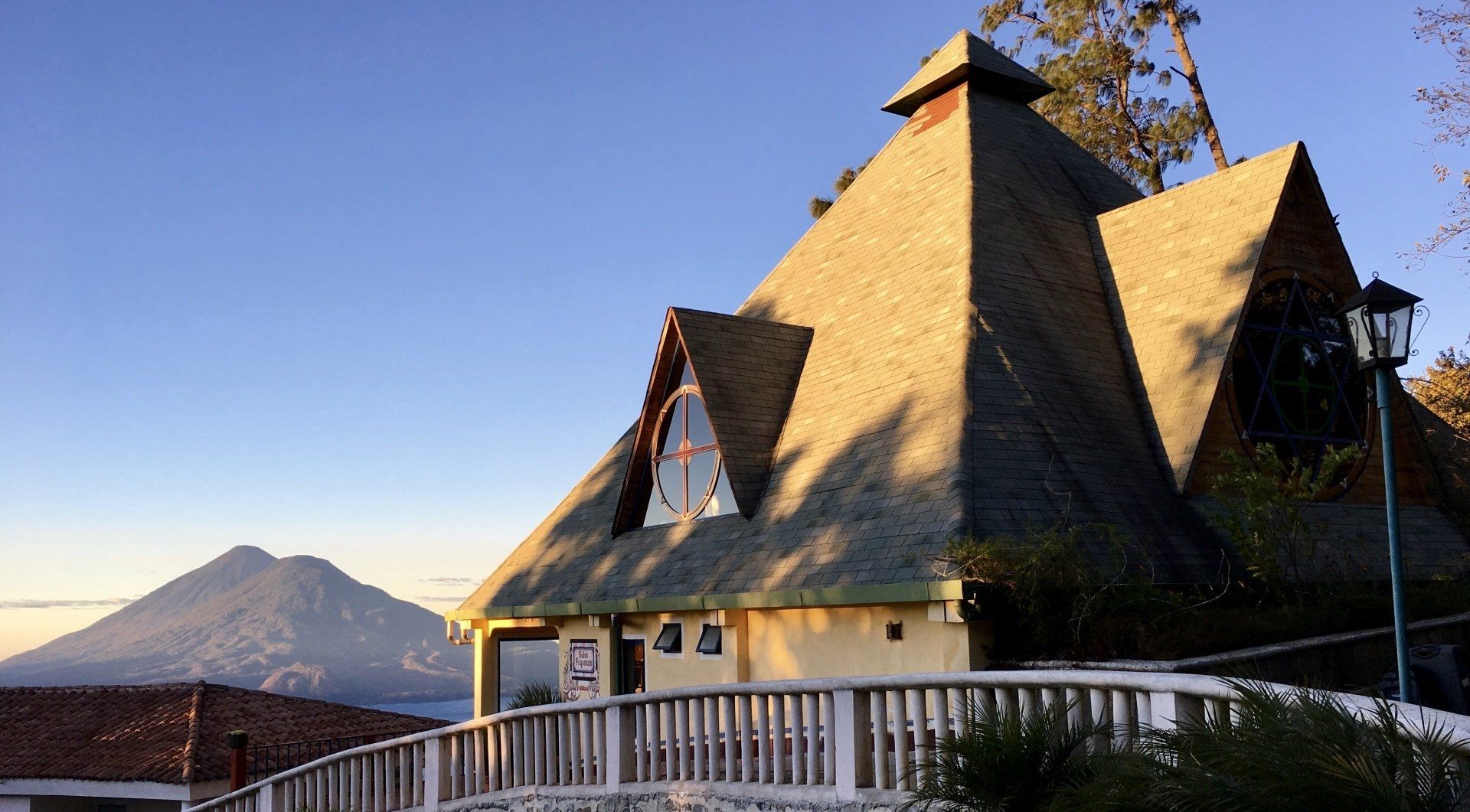 Ein Haus mit Strohdach ist von Bäumen und Bergen umgeben