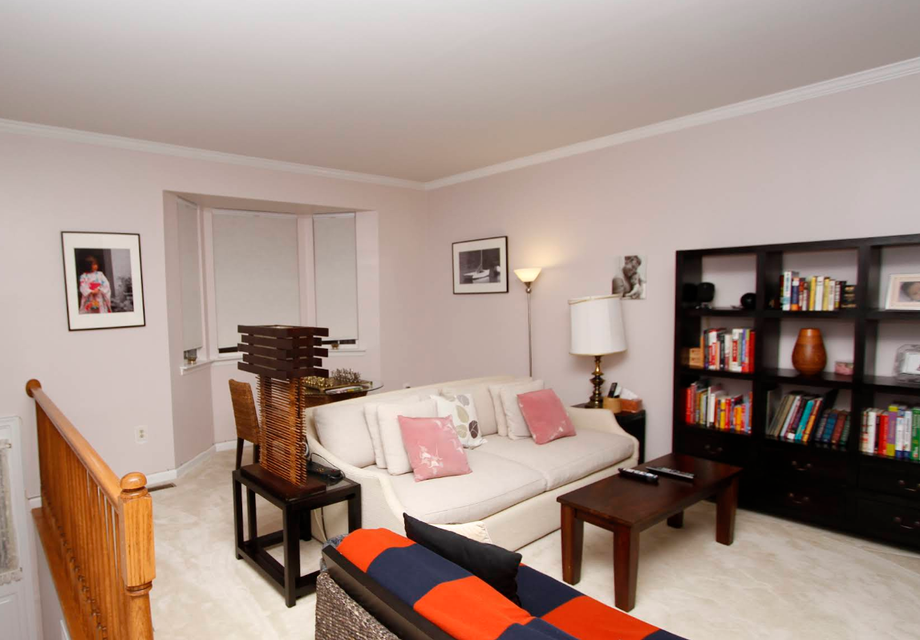 Living room with a sofa, bookshelf, and a wooden staircase railing.