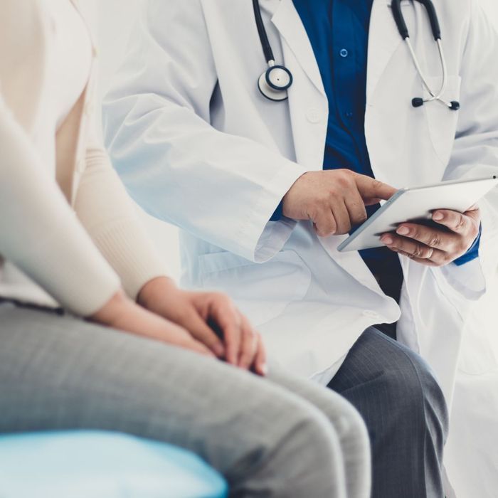 A doctor is using a tablet while talking to a patient