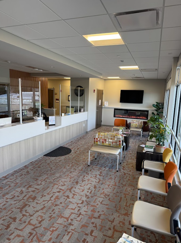 A waiting room with chairs , tables , a fireplace and a television.
