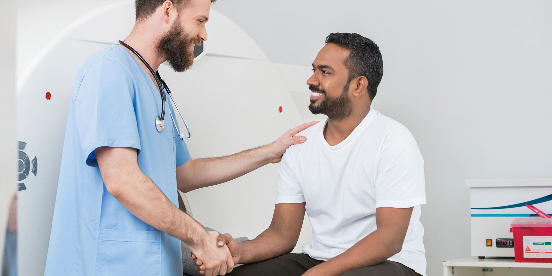 A doctor is shaking hands with a patient in front of an mri machine.