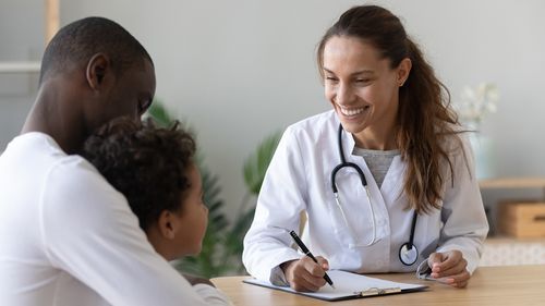 A doctor is talking to a man and a child at a table.