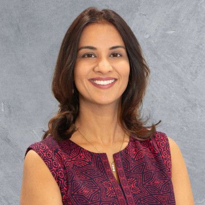 A woman in a red top is smiling for the camera.