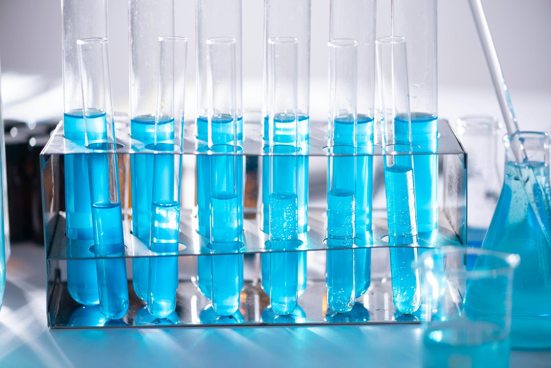 A row of test tubes filled with blue liquid on a table.