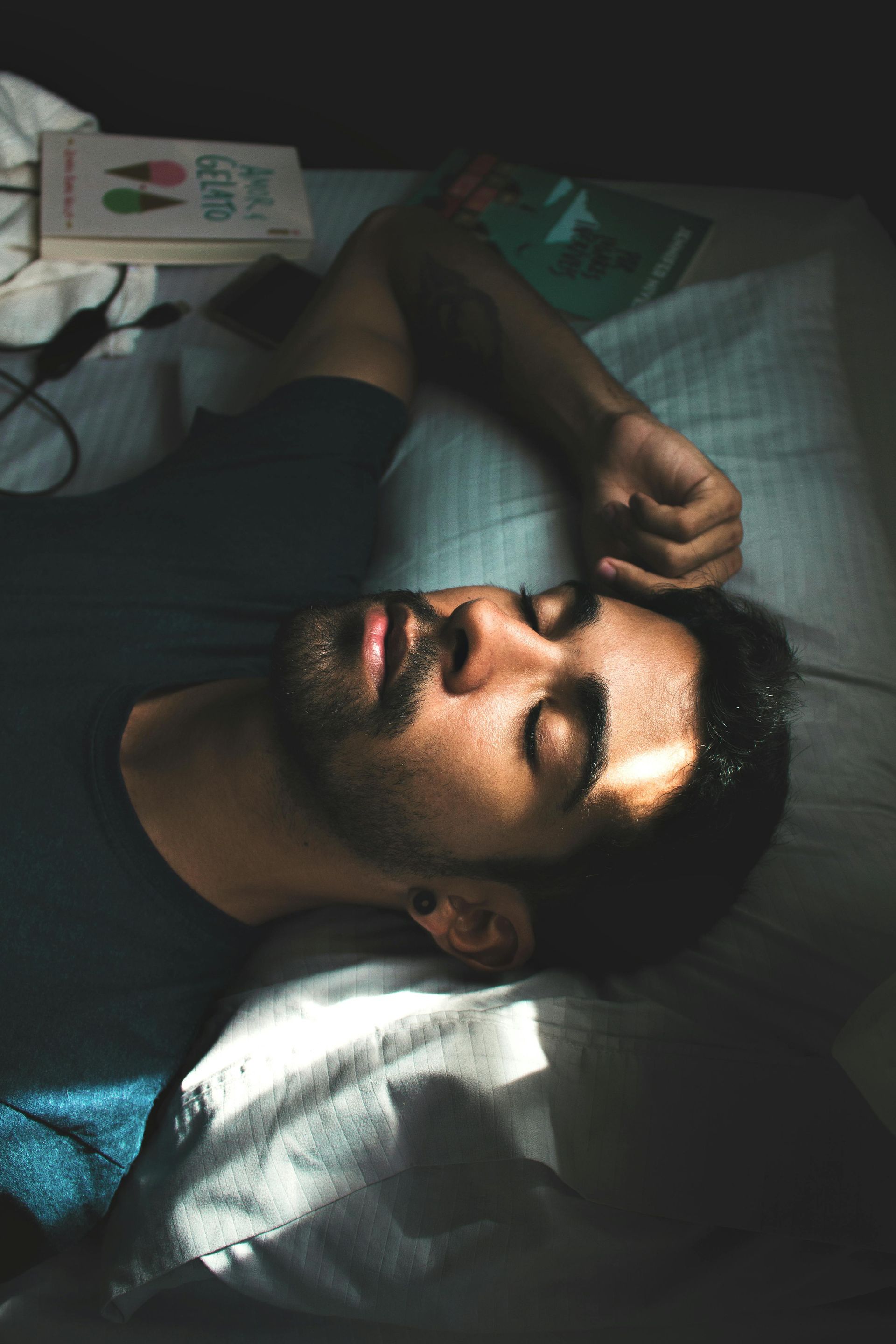 A man is laying on a bed with his eyes closed.