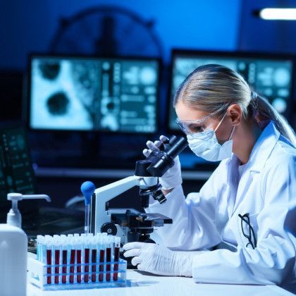 A female scientist is looking through a microscope in a laboratory.
