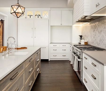 A kitchen with white cabinets , stainless steel appliances , and a large island.