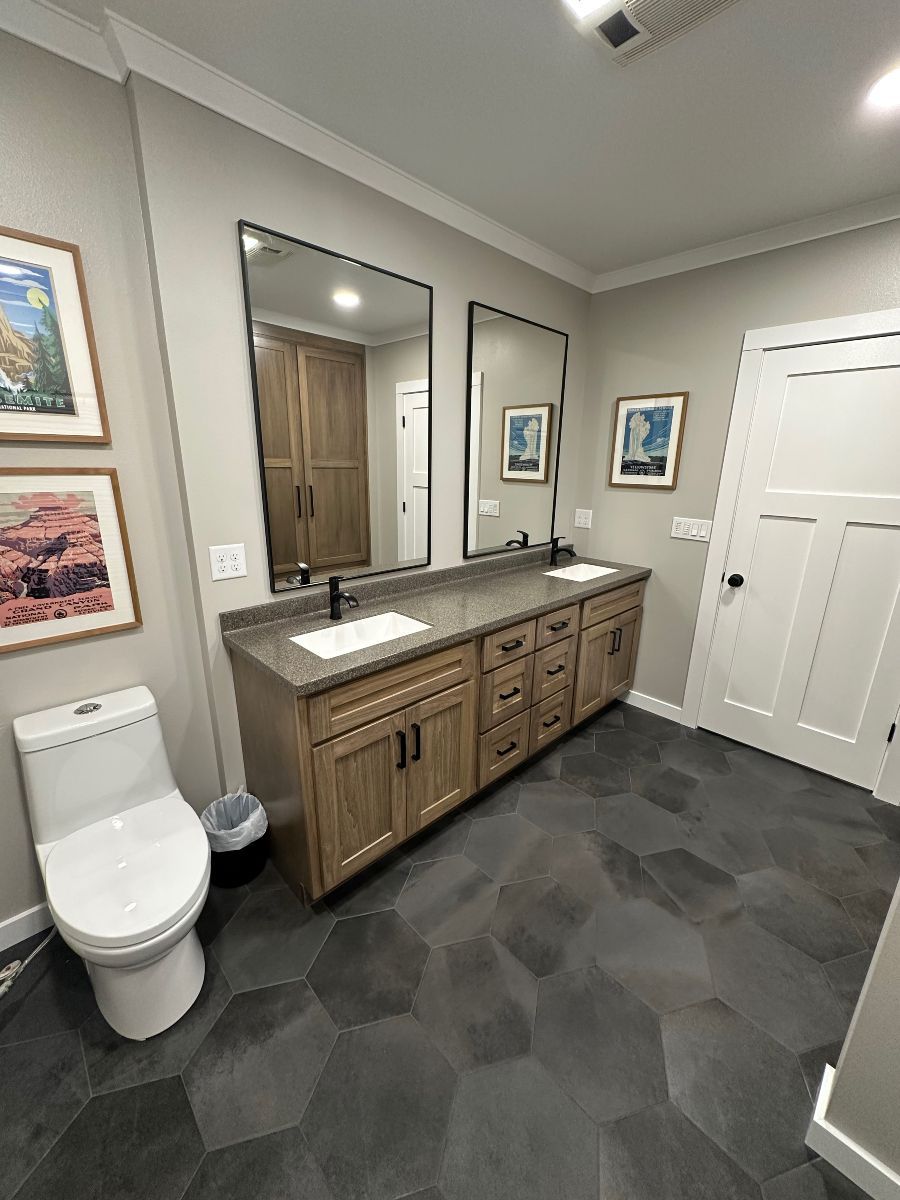 A bathroom with two sinks , a toilet , and two mirrors.