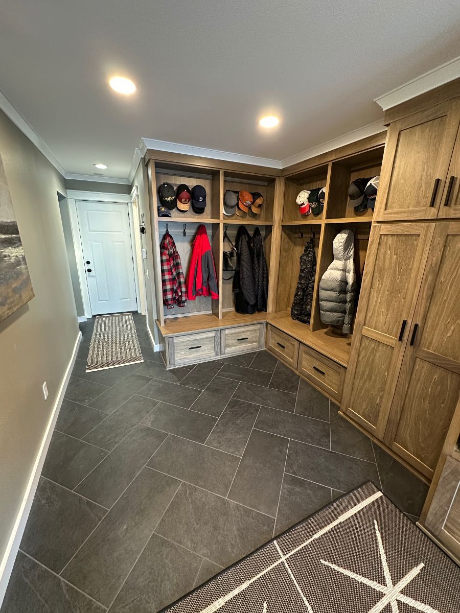 A hallway with lots of shelves and cabinets and a rug.