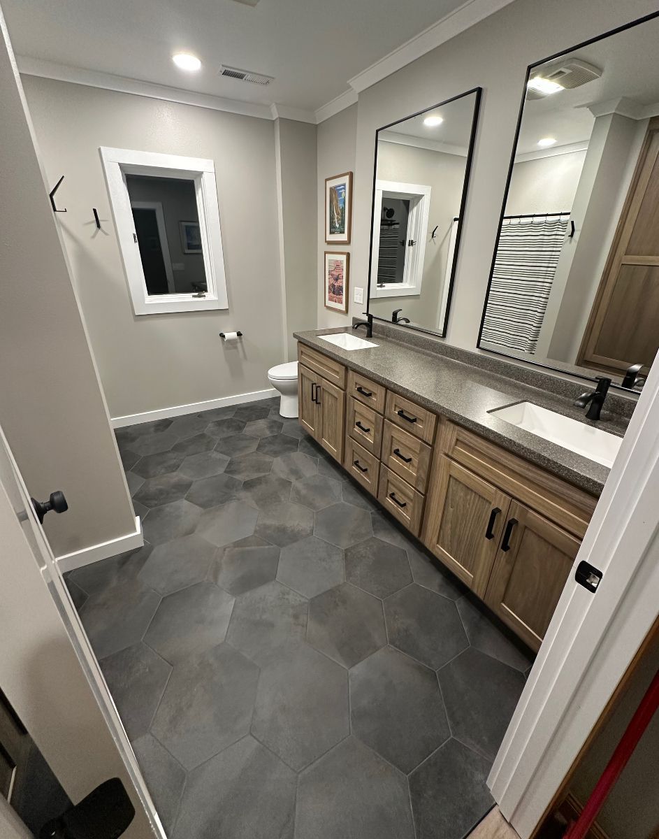 A bathroom with two sinks , a toilet , and two mirrors.