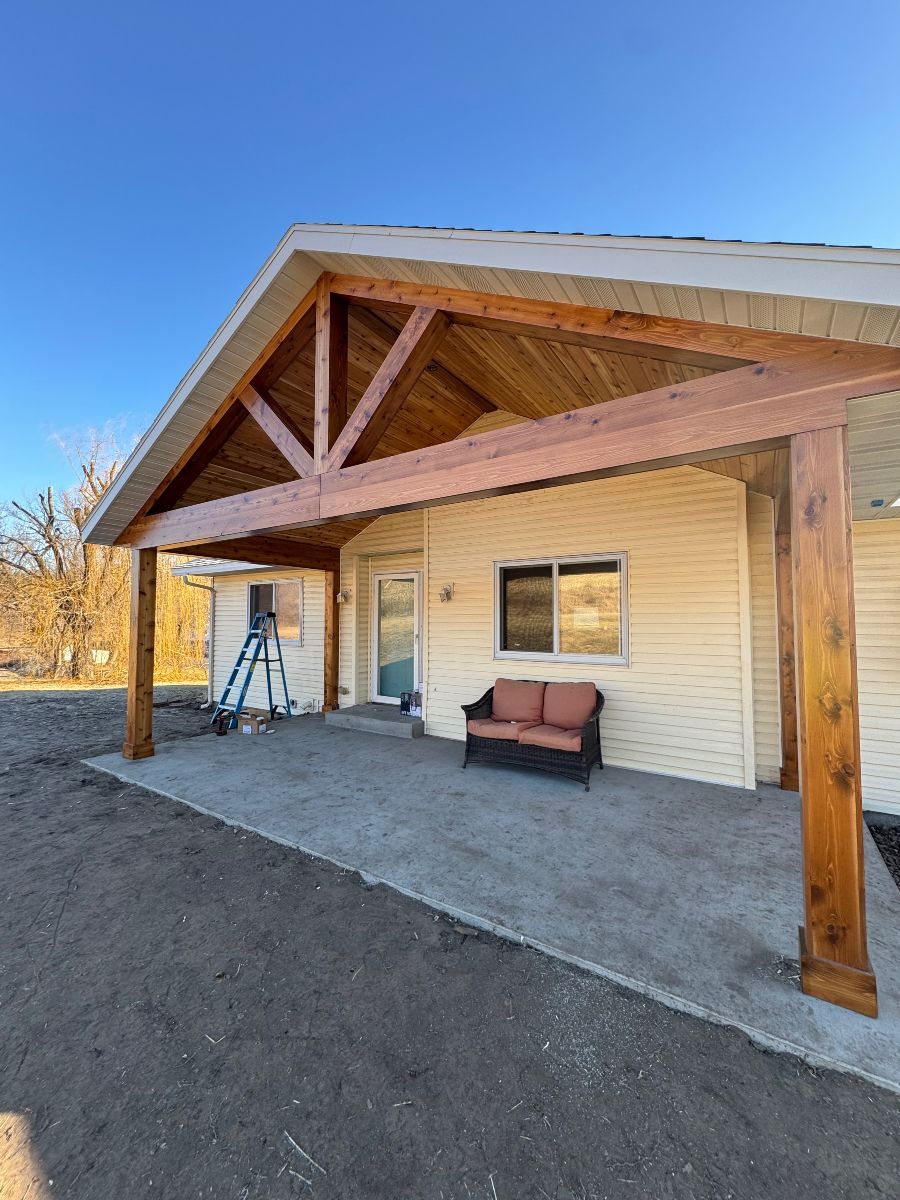 A house with a covered porch and a couch in front of it.