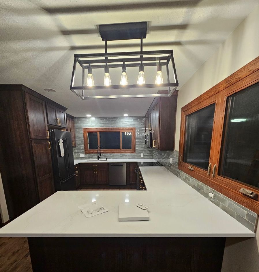 A kitchen with a white counter top and a black refrigerator